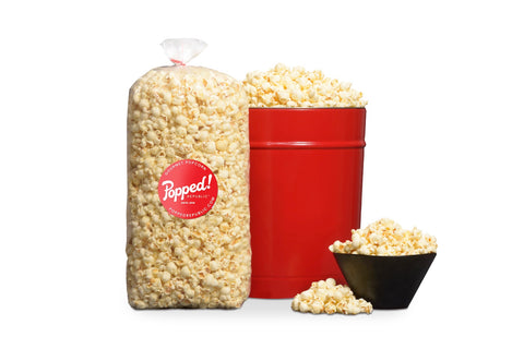Red bucket and an extra large bulk bag of Gourmet savory white cheddar flavored popcorn from Popped! Republic