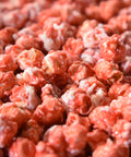 Close up of red cherry gourmet popcorn kernels covered in white chocolate