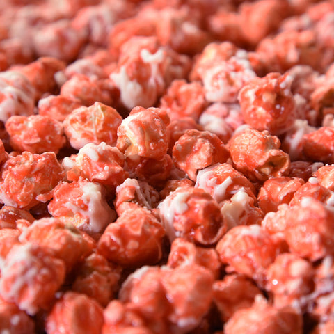Close up of red cherry gourmet popcorn kernels covered in white chocolate