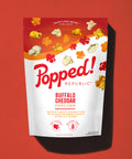 Stand up pouch of gourmet Buffalo Cheddar  popcorn on a red background
