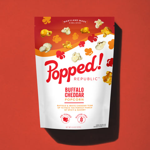 Stand up pouch of gourmet Buffalo Cheddar  popcorn on a red background