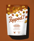 Stand up pouch of Gourmet Caramel popcorn on a brown background